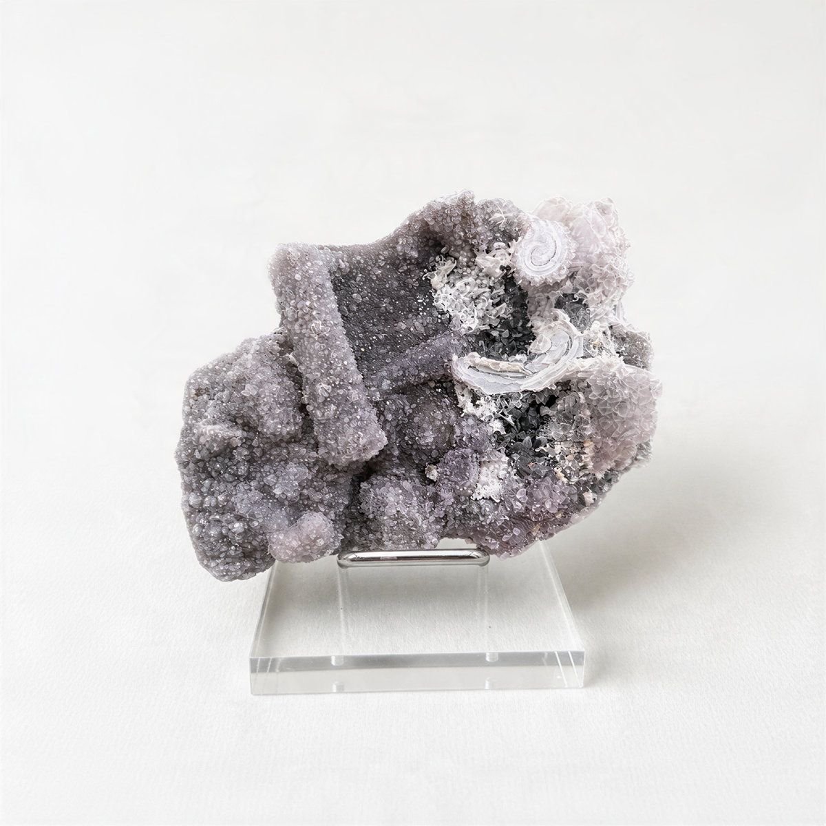 a clear glass display case containing a large, irregularly shaped crystal with a mix of white and gray hues.