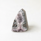A single, unique crystal formation with a jagged, triangular shape and a mix of purple and gray hues.