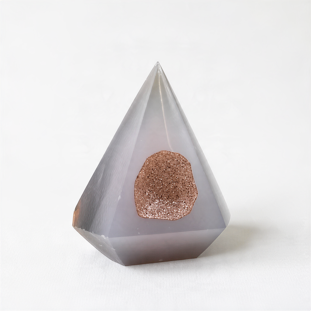 A gray, triangular crystal with a small, round, brownish-colored object in the center.