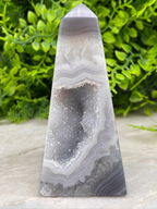 A triangular, pointed crystal formation with a unique, striped pattern, set against a blurred green background.