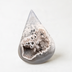A clear, triangular-shaped rock formation with a white and gray speckled surface, resembling a crystal or gemstone.