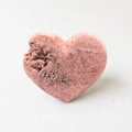 A heart-shaped object made of a pink material, possibly clay or a similar material, with a bite taken out of it.