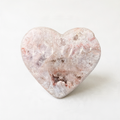 A heart-shaped stone with a pinkish-brown hue and a rough, textured surface.