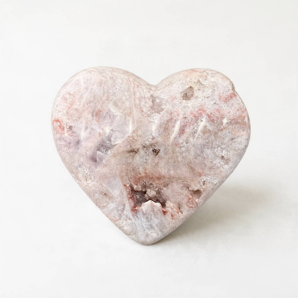 A heart-shaped stone with a pinkish-brown hue and a rough, textured surface.