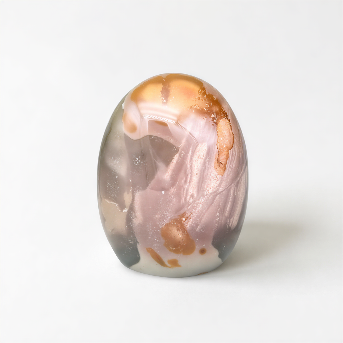 a round, glass-like object with a pink and orange color scheme, sitting on a white surface.