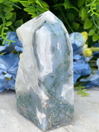 a close-up view of a jadeite crystal surrounded by blue flowers.