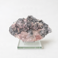 a clear glass stand displaying a piece of rock with a unique, multicolored crystal structure.