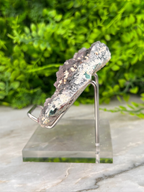 A piece of rock with a unique, irregular shape and a mix of gray and green colors, displayed on a clear stand.