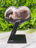 a heart-shaped rock held in place by a black metal stand.