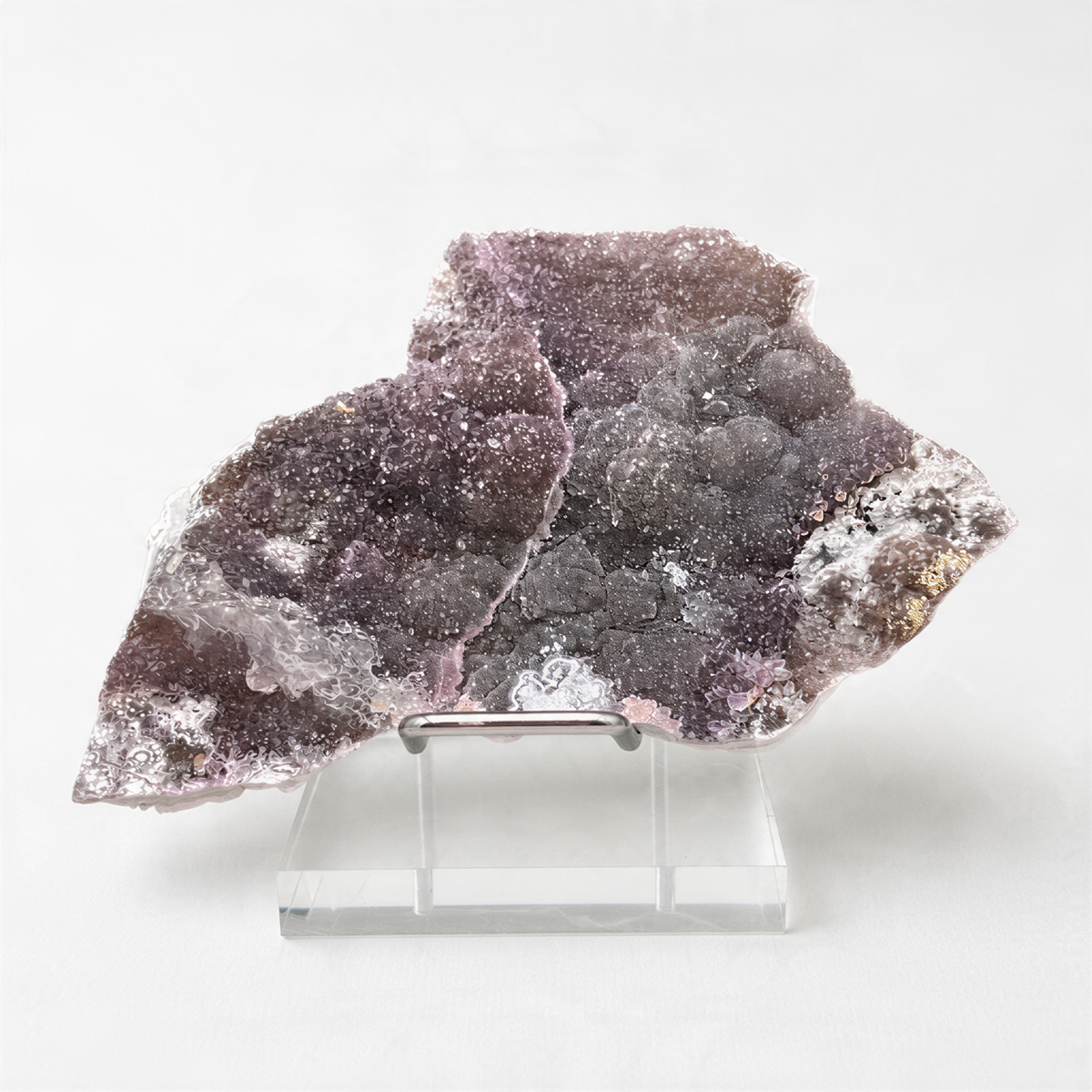 a clear glass display case containing a large, irregularly shaped crystal with a purple and gray coloration.