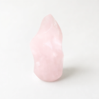 A single, light pink crystal sits alone on a plain white background.