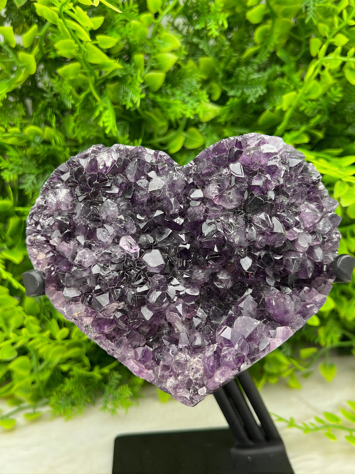 The image shows a heart-shaped crystal formation made of purple amethyst crystals.