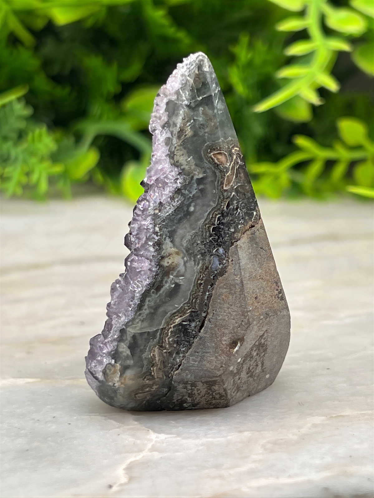 A close-up image of a rock formation with a jagged, irregular shape, displaying a mix of gray, black, and purple hues.