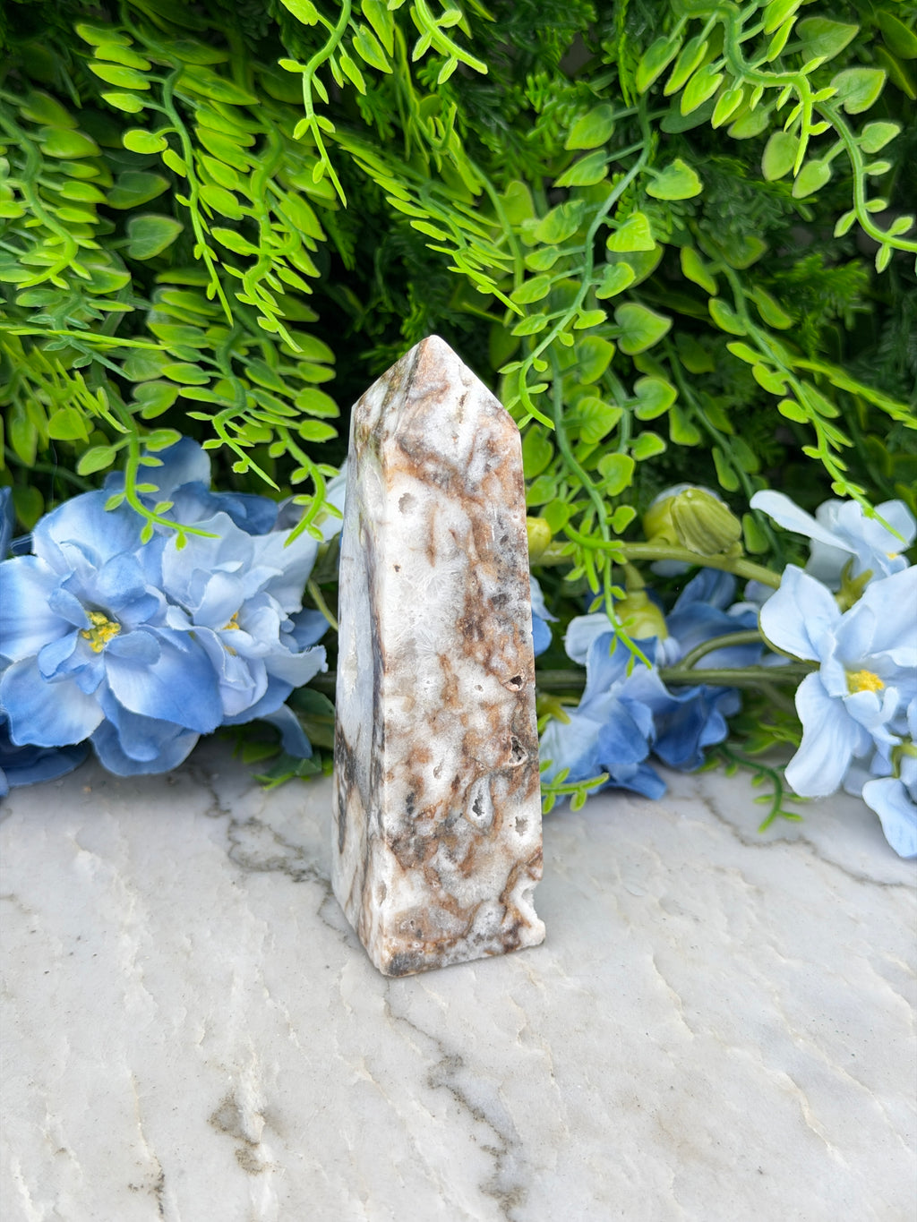 a close-up view of a stone or rock formation surrounded by lush green foliage and vibrant blue flowers.
