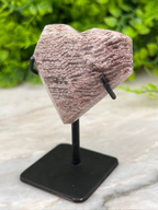 a heart-shaped rock sitting on top of a black stand