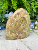 a large, irregularly shaped rock with a greenish hue, placed on a marble surface.