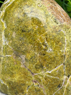 a close-up view of a rock with a greenish-brown hue, featuring a textured surface with visible cracks and fractures.