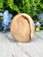 a large, oval-shaped stone with a brownish-brown hue, placed on a marble surface. The stone is surrounded by a variety of blue flowers, creating a visually appealing contrast.