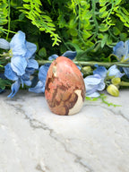 a brown and white speckled rock sitting on a marble surface, surrounded by blue flowers.