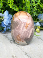 A jadeite, a type of jadeite, is displayed on a marble surface surrounded by blue flowers.