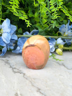 a stone or rock with a unique, textured surface, surrounded by a variety of colorful flowers and foliage.