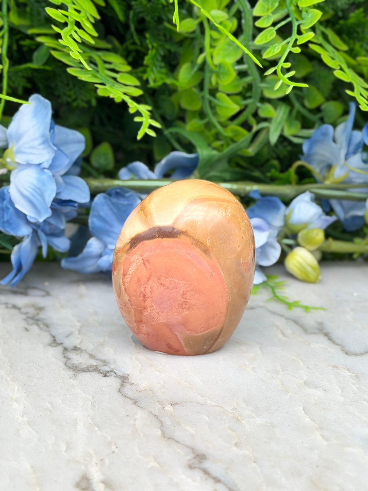 a stone or rock with a unique, textured surface, surrounded by a variety of colorful flowers and foliage.