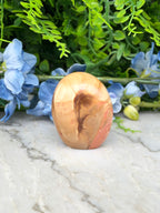 a marble-like stone or rock with a unique, swirling pattern, surrounded by a variety of blue flowers and greenery.