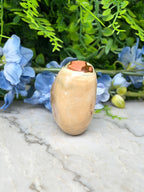 a light brown stone with a small hole in the center, surrounded by a variety of blue flowers and green foliage.