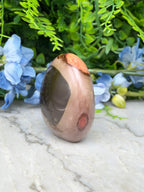 A jadeite, a type of jadeite gemstone, is displayed on a marble surface surrounded by blue flowers.