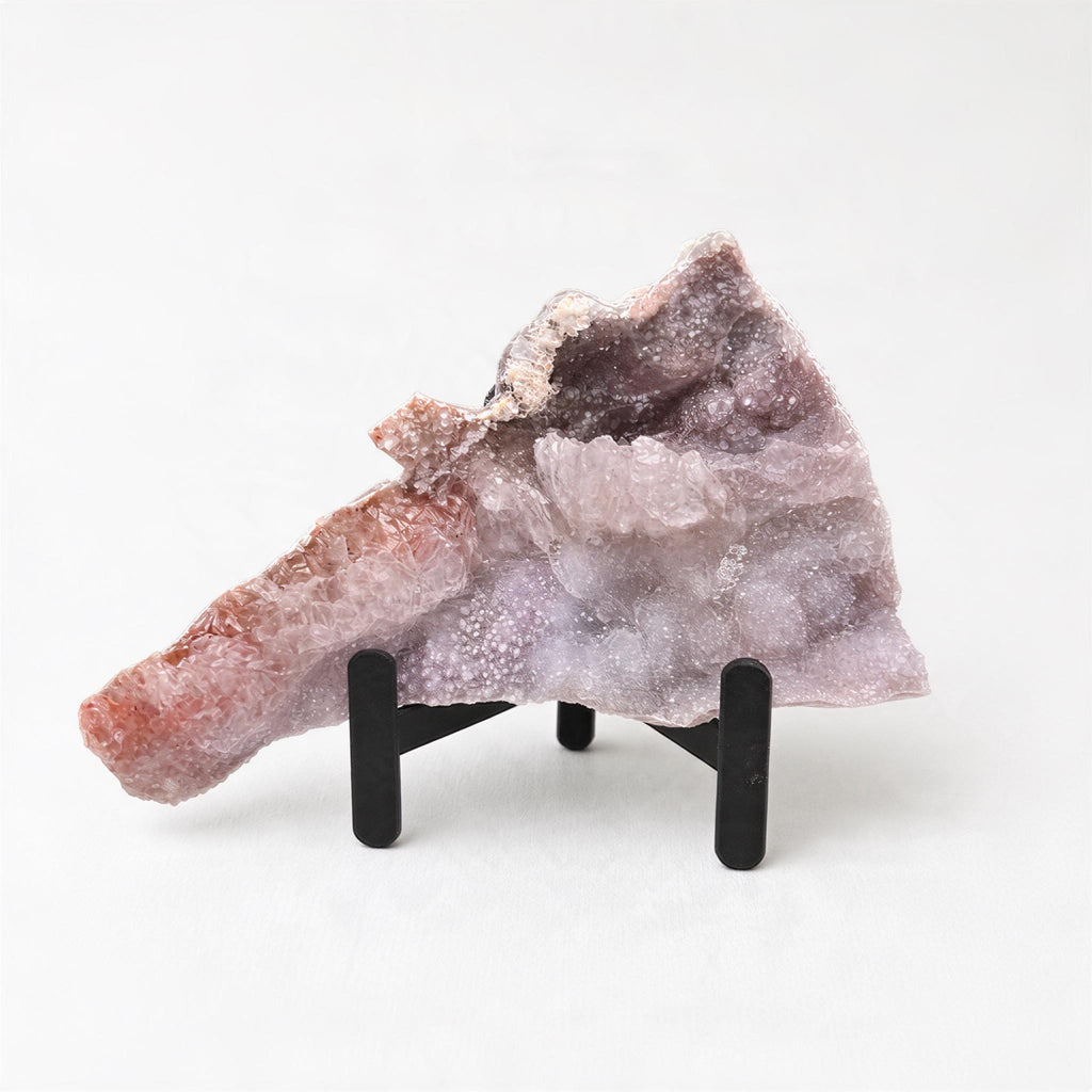 a piece of amethyst, a purple crystal, displayed on a black stand.