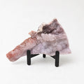 a piece of amethyst, a purple crystal, displayed on a black stand.