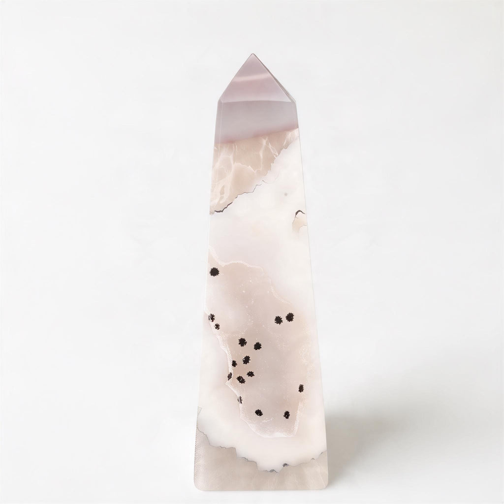 A tall, pointed crystal formation with a pinkish-white hue and scattered black dots on its surface.
