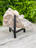 a large, irregularly shaped rock or crystal on a stand, placed on a marble surface.