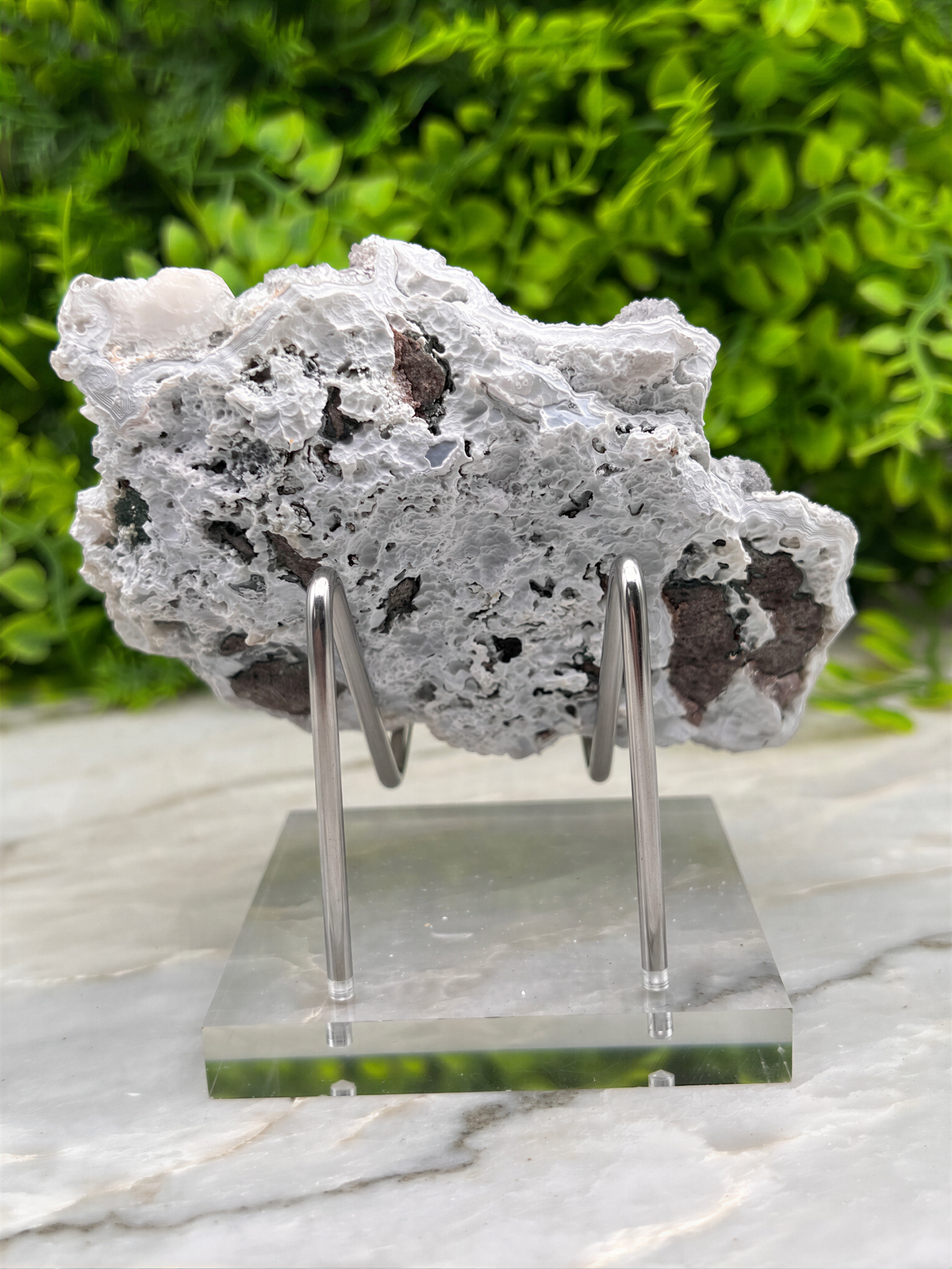 a piece of white rock with black spots, displayed on a clear glass stand.