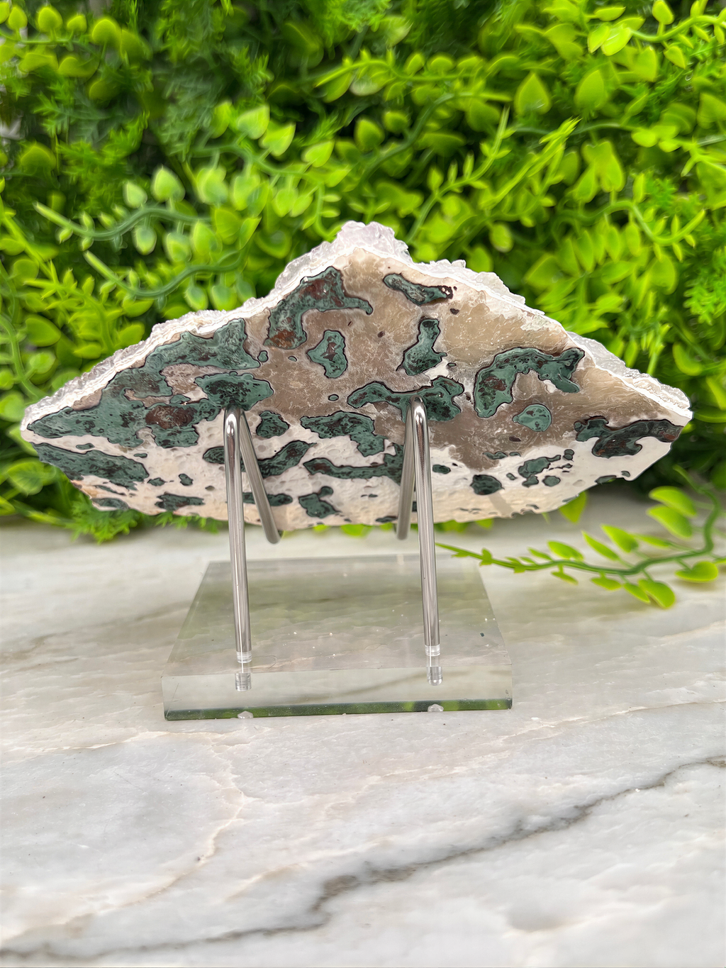 a piece of rock with a unique, multicolored pattern, displayed on a clear stand.