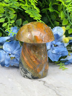 a close-up view of a natural stone mushroom-shaped object, surrounded by vibrant blue flowers.