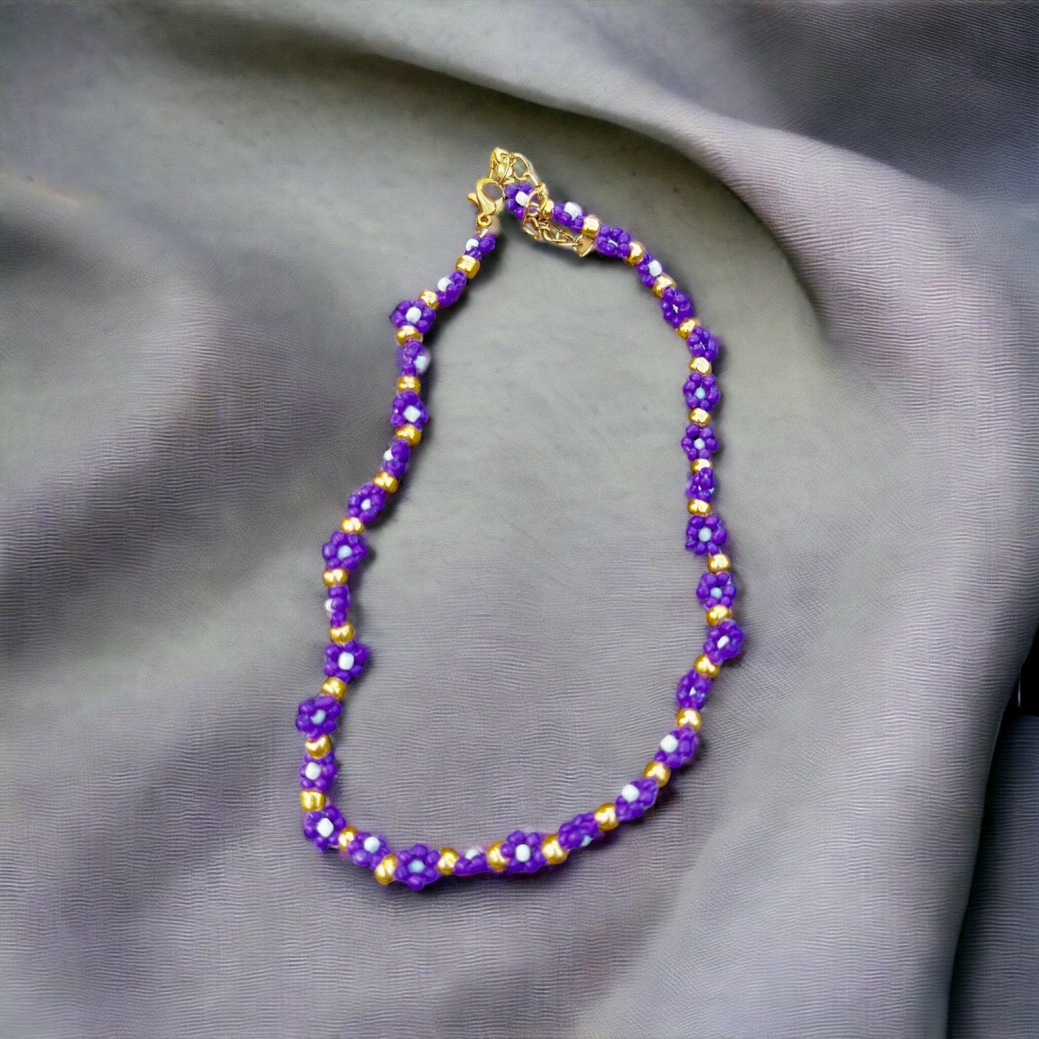 Halskette mit lila, weißen und goldenen Blumen