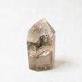 a clear crystal with a greenish tint, resting on a white surface.
