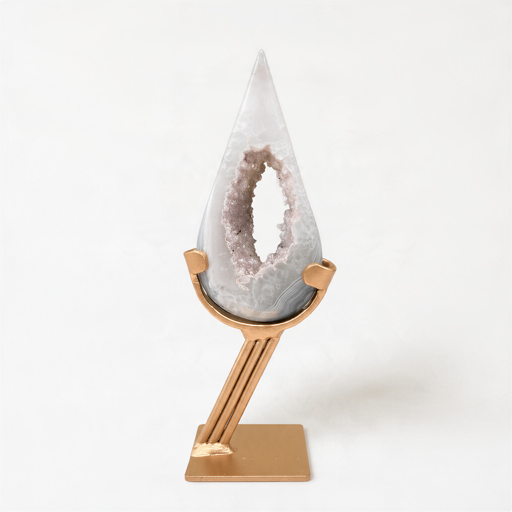 A white geode with a hole in the center is displayed on a gold stand against a white background.