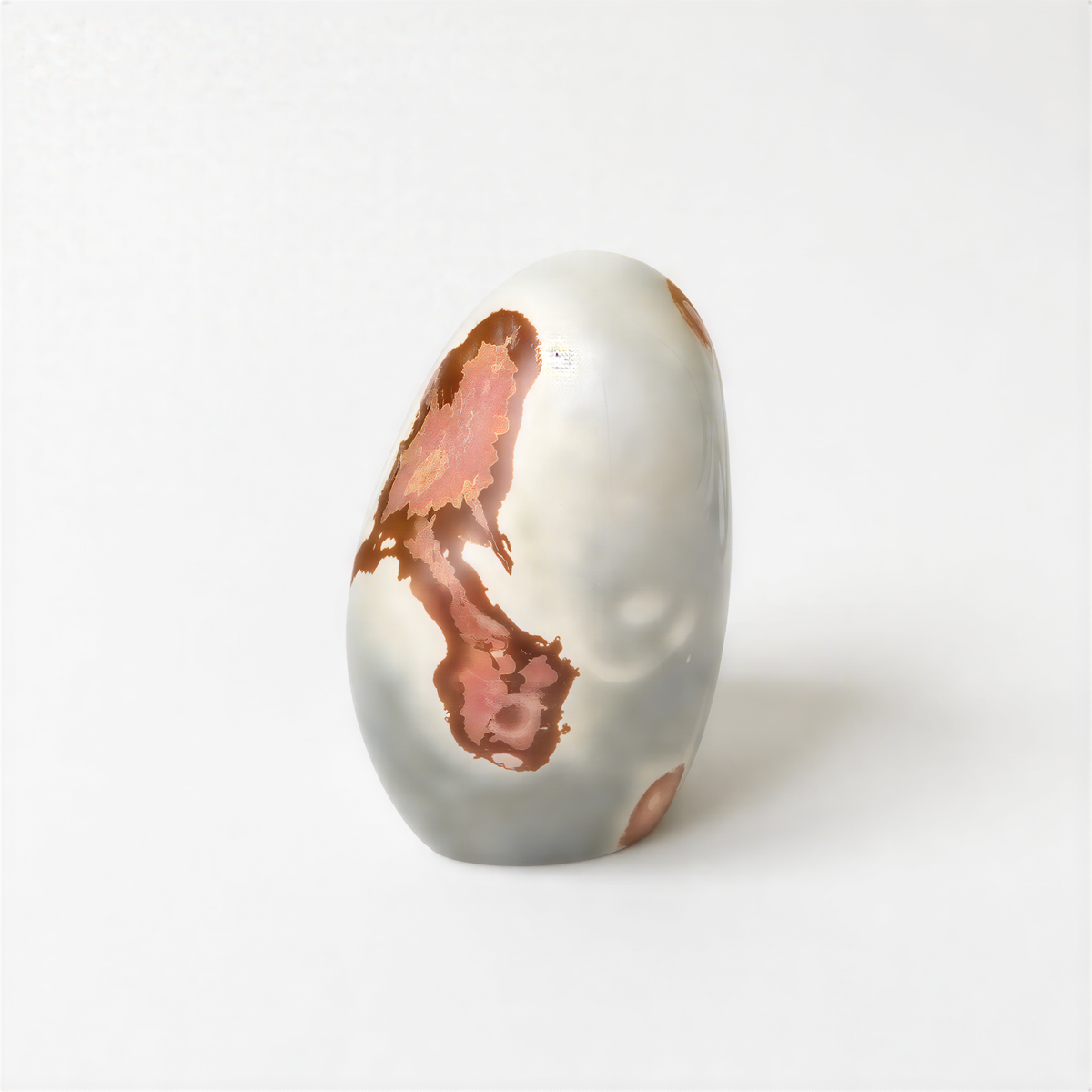 a white, oval-shaped object with a reddish-brown, abstract design on its surface.
