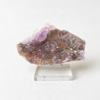 a clear glass display case containing a piece of purple crystal or gemstone.
