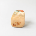 A single, light-colored stone with a small, brown spot on it, sitting on a plain white background.